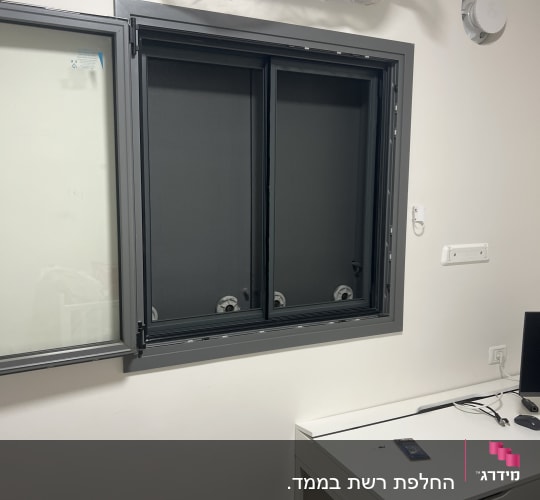 חלון אלומיניום עם מסגרת אפורה על קיר לבן